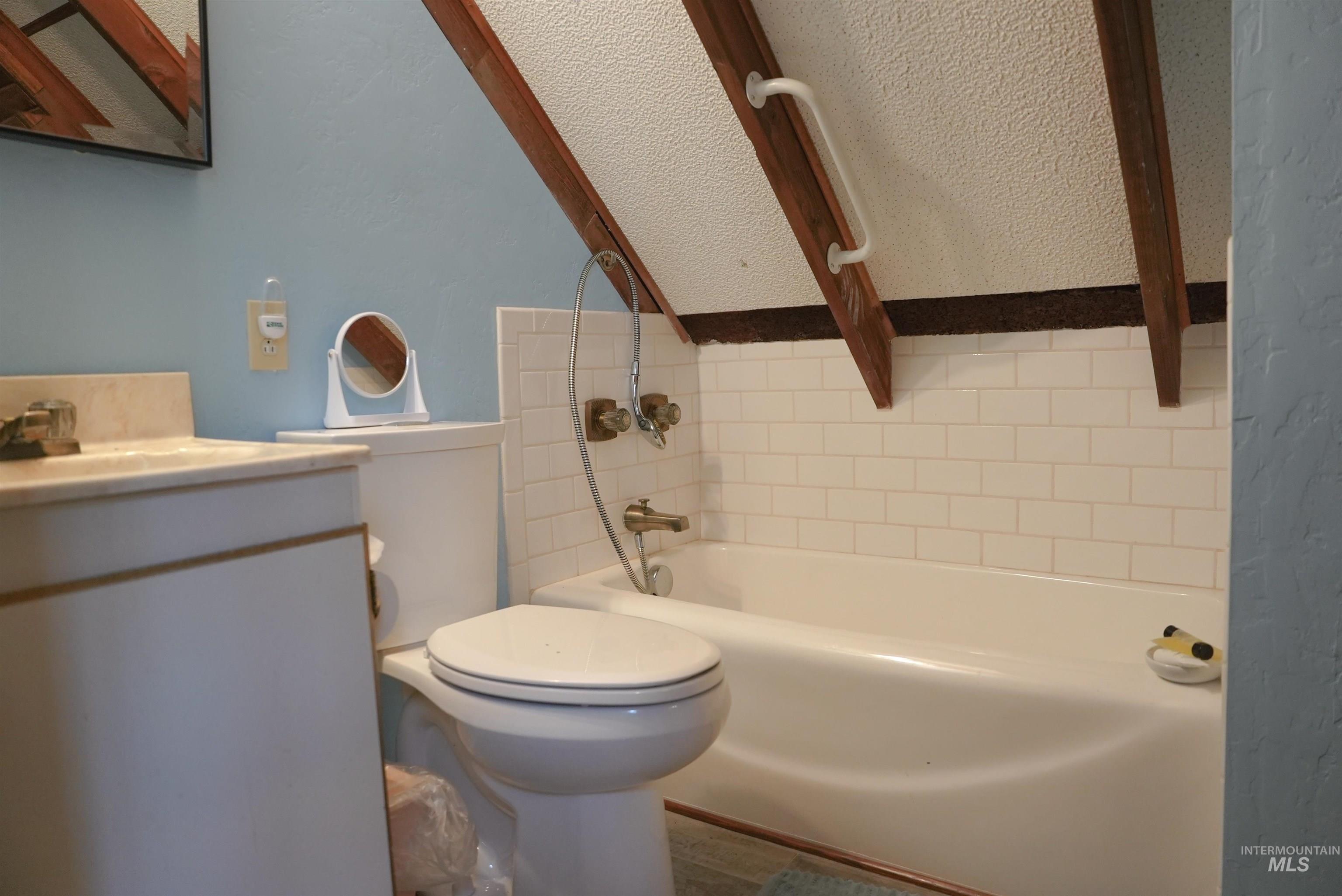 Full bath with vanity, a textured ceiling, and bathtub / shower combination