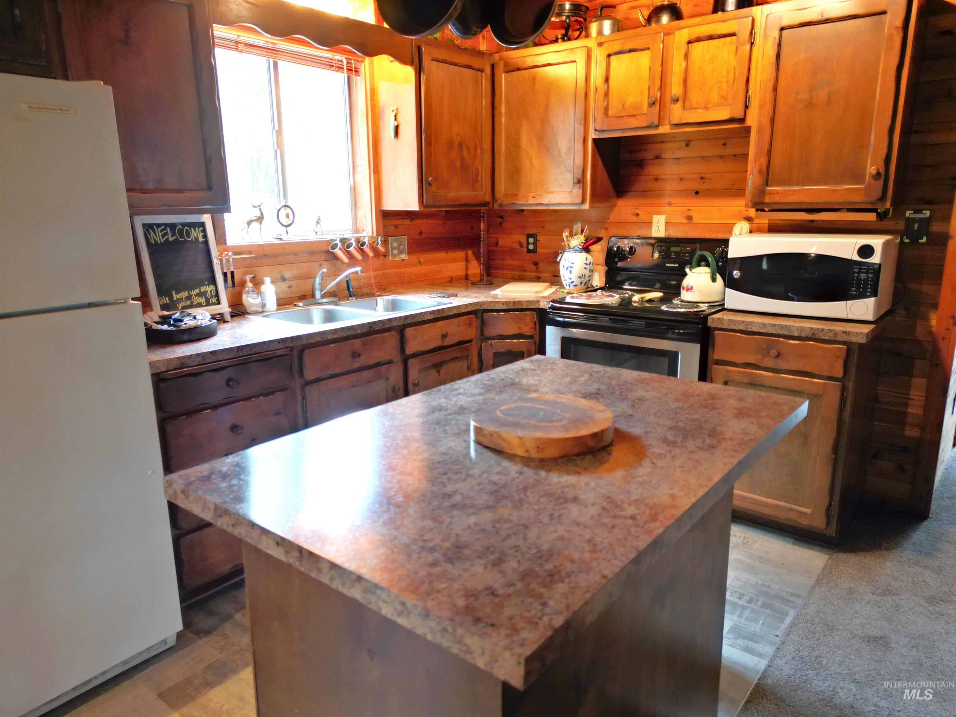Kitchen featuring white appliances, brown cabinetry, a kitchen island, and wood walls