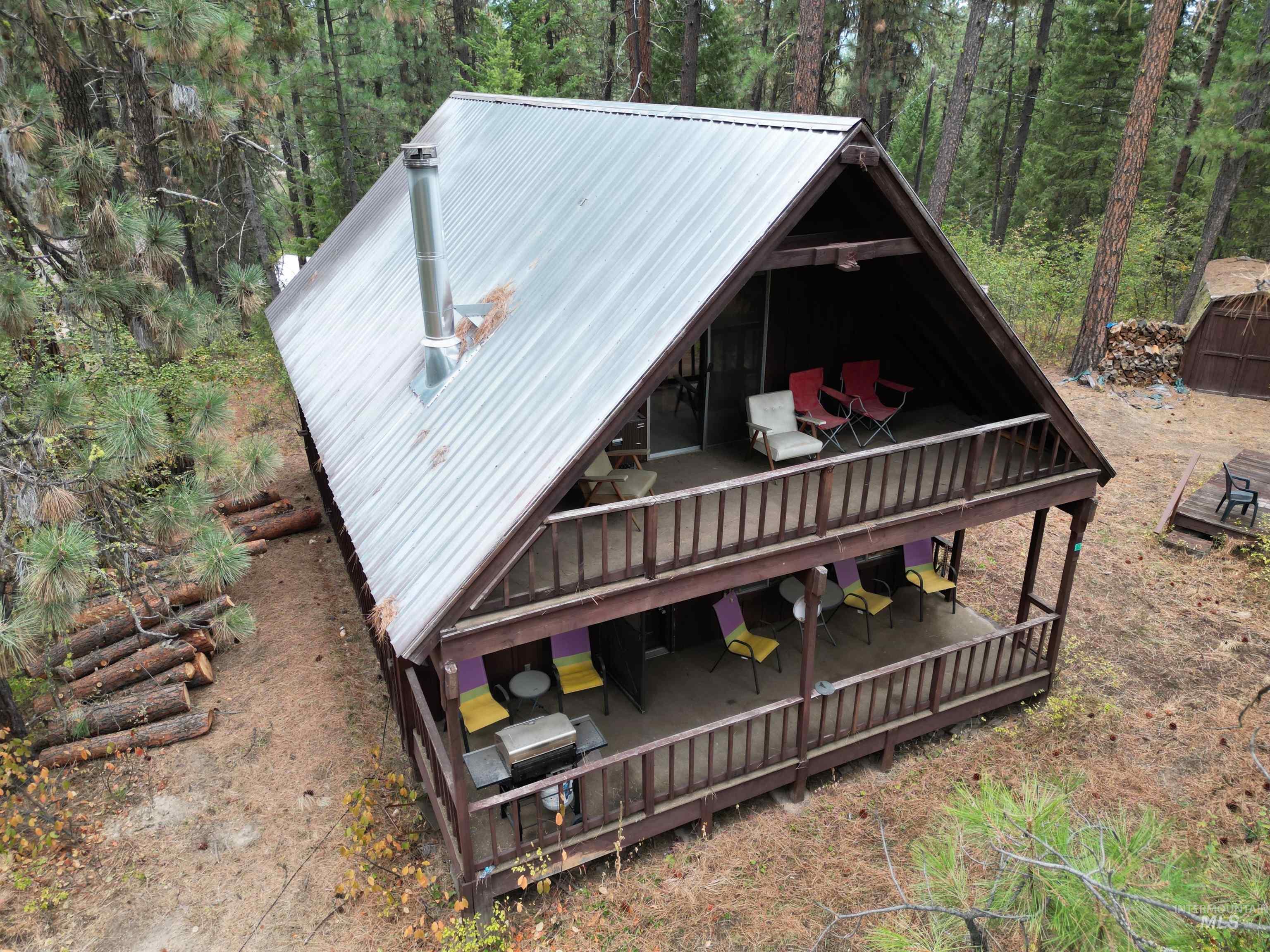 View of front of property with a metal roof, a deck, and a forest view