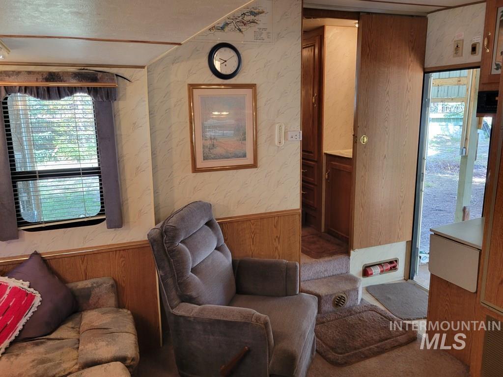 Sitting room with wooden walls, wainscoting, healthy amount of natural light, and wallpapered walls