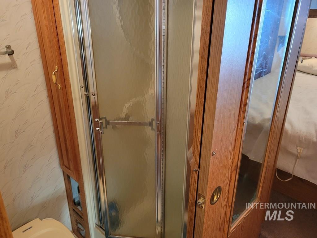 Full bathroom with wallpapered walls and a stall shower