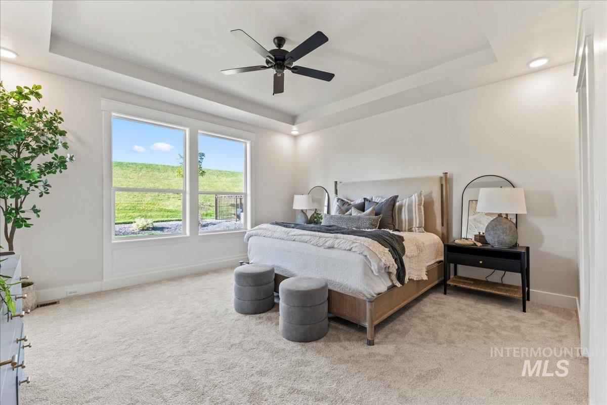 Bedroom with a raised ceiling, light carpet, a ceiling fan, and recessed lighting