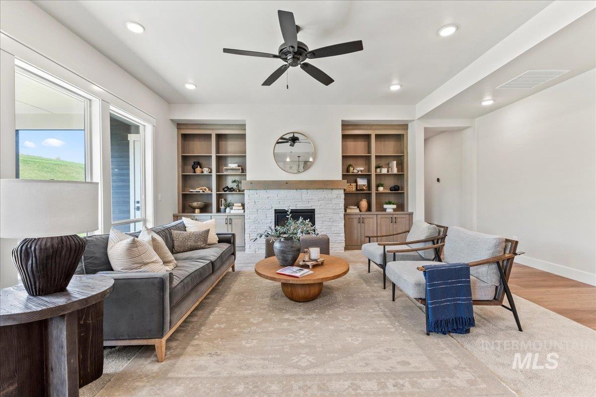 Living area featuring light wood-style floors, a fireplace, recessed lighting, ceiling fan, and built in shelves