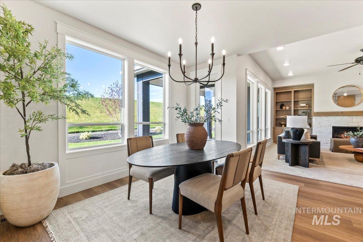 Dining space featuring plenty of natural light, light wood finished floors, a stone fireplace, and recessed lighting