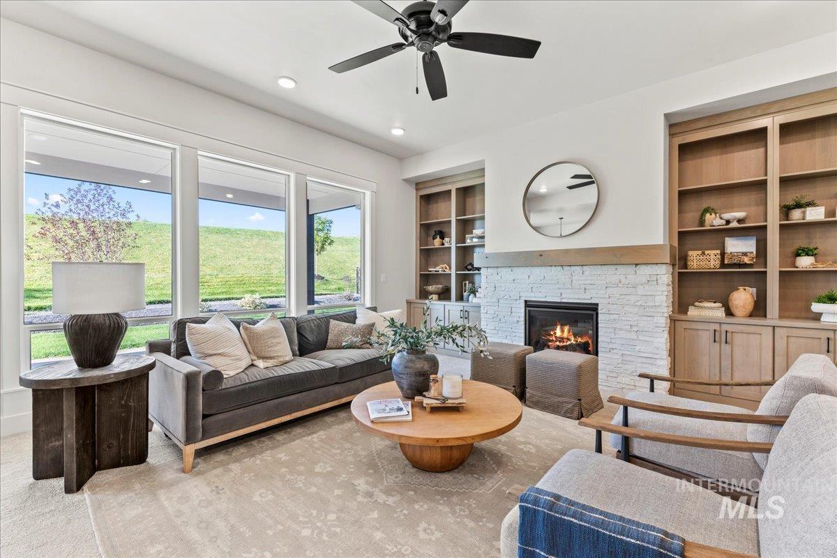 Carpeted living room featuring a fireplace, built in shelves, recessed lighting, and a ceiling fan