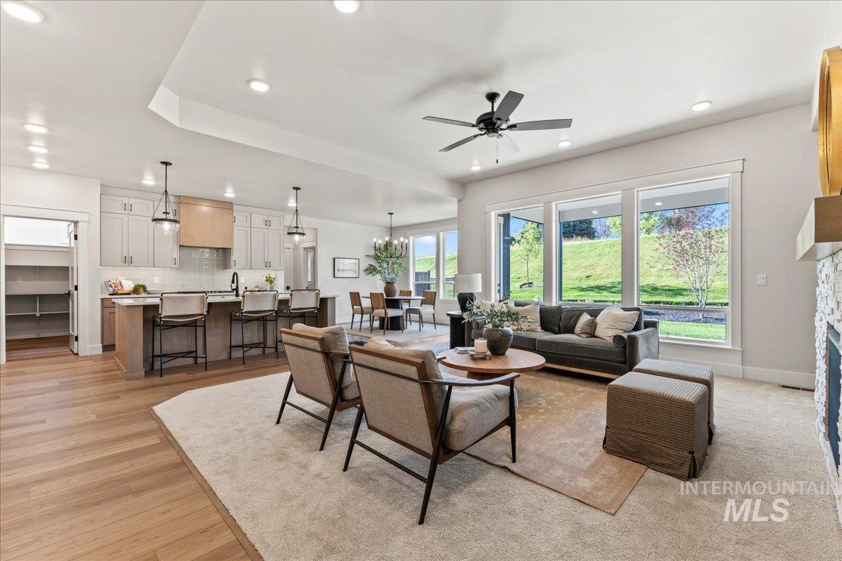 Living area with a ceiling fan, recessed lighting, a chandelier, and a stone fireplace