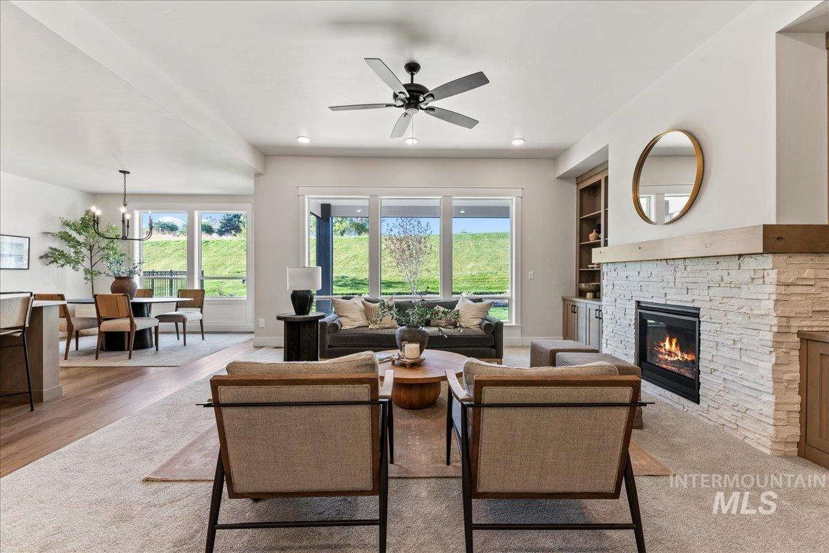 Living room with plenty of natural light, a stone fireplace, a ceiling fan, light wood-style flooring, and recessed lighting