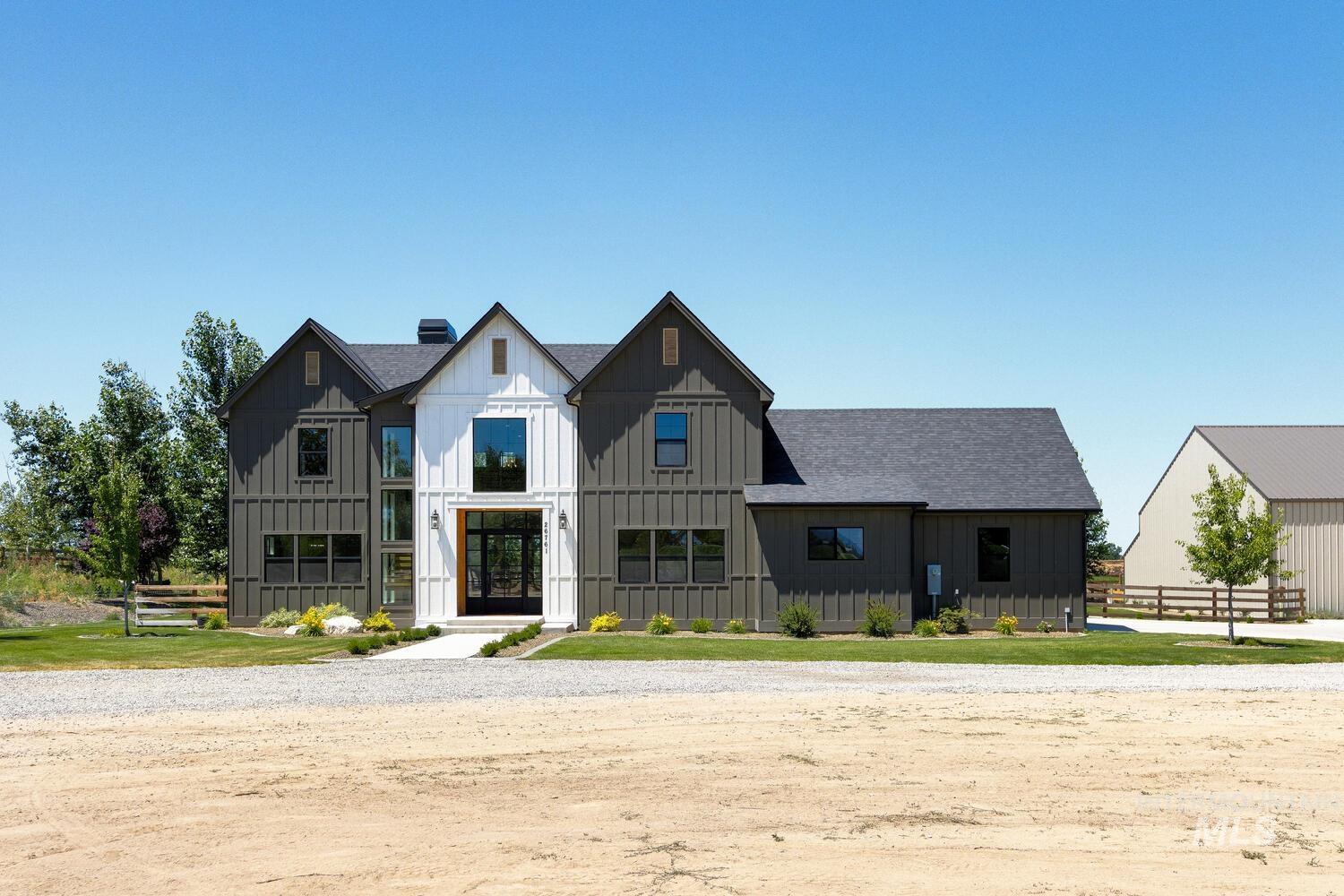 Modern farmhouse style home featuring board and batten siding, roof with shingles, and a chimney
