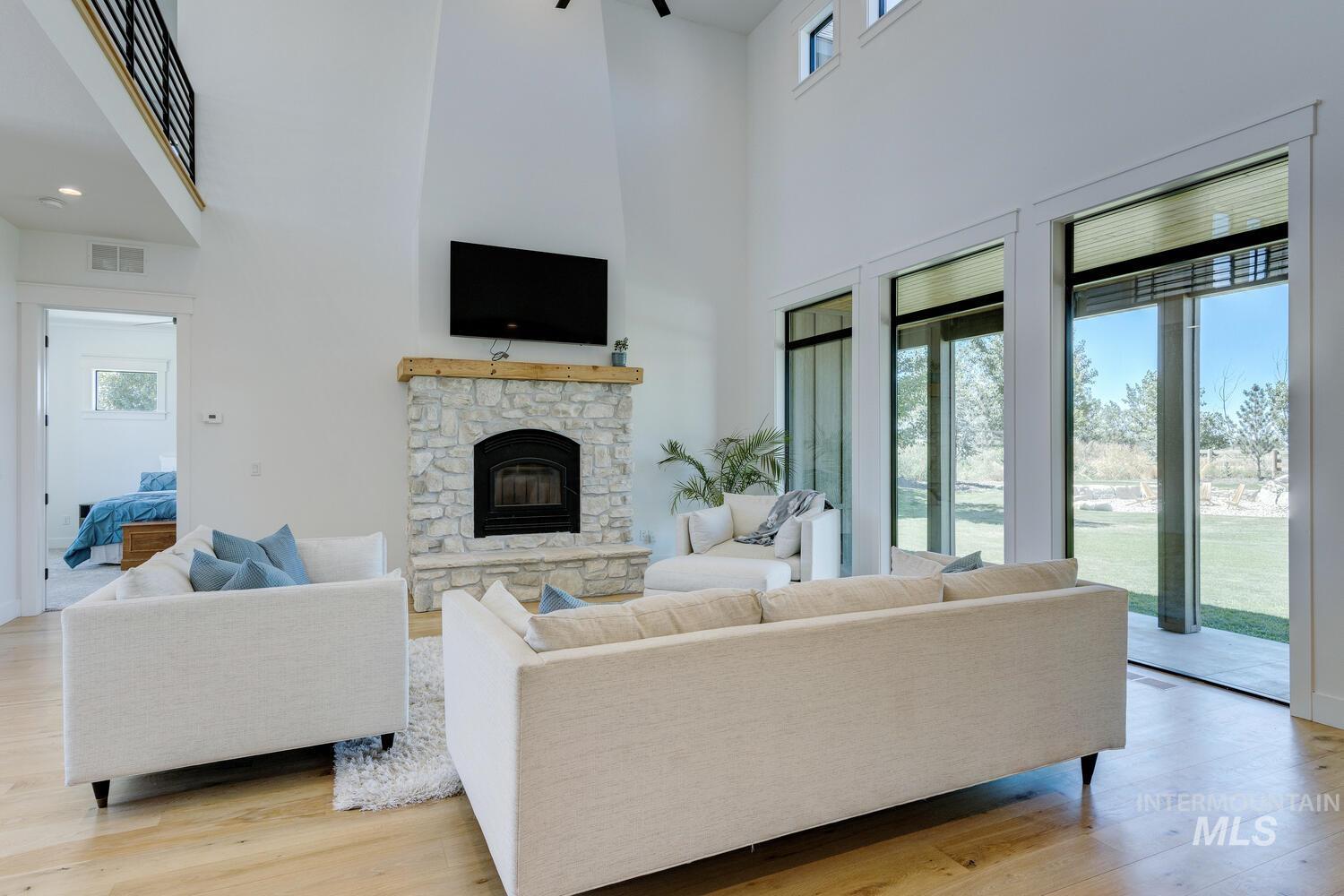 Living area with a high ceiling, a fireplace, and light wood finished floors