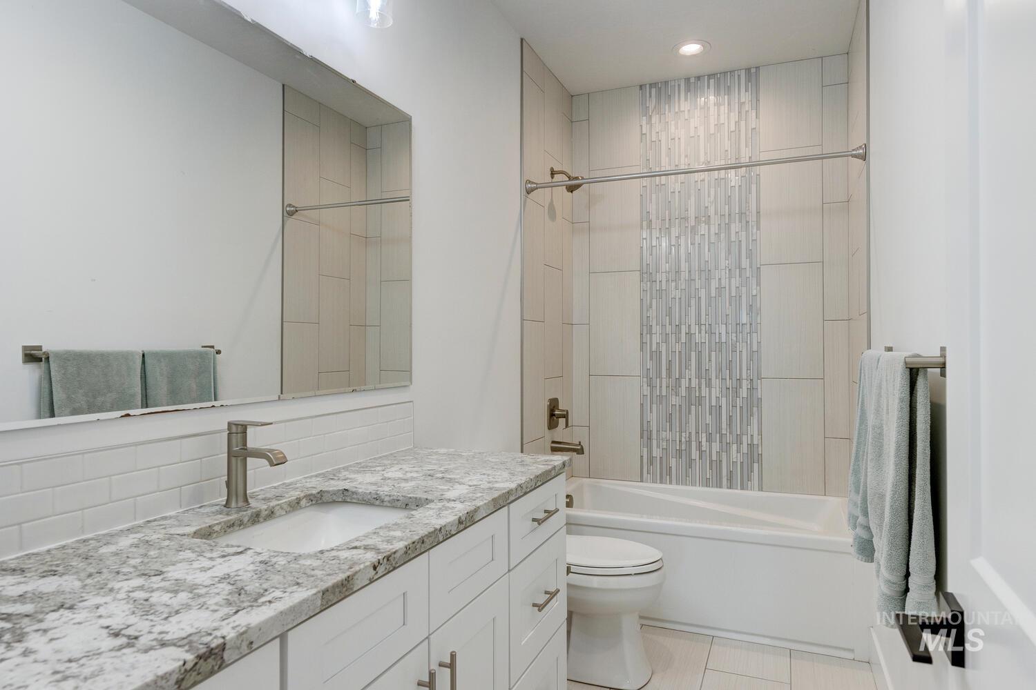 Bathroom featuring vanity, shower / washtub combination, recessed lighting, and backsplash