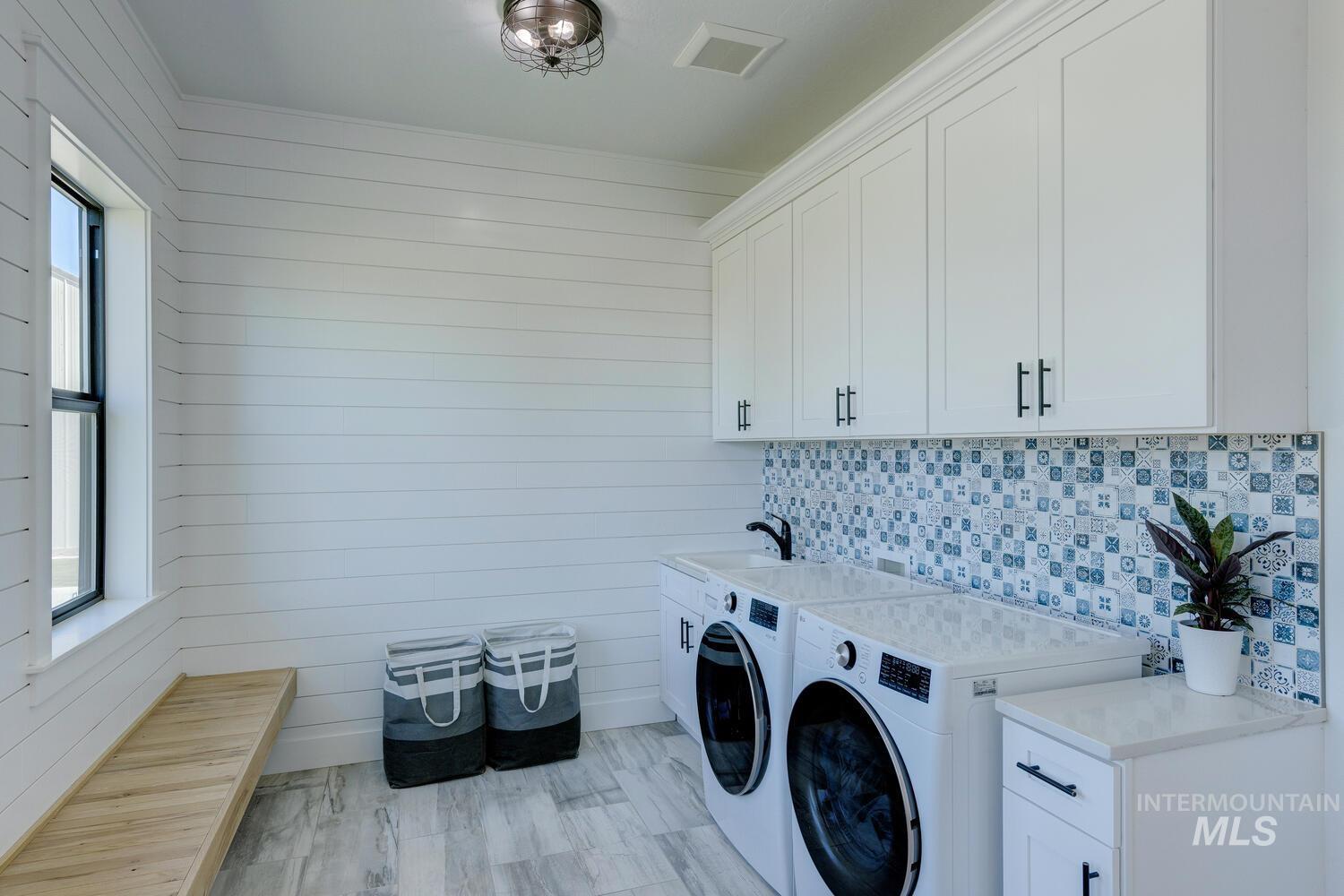 Laundry area with washer and clothes dryer, cabinet space, plenty of natural light, and wooden walls