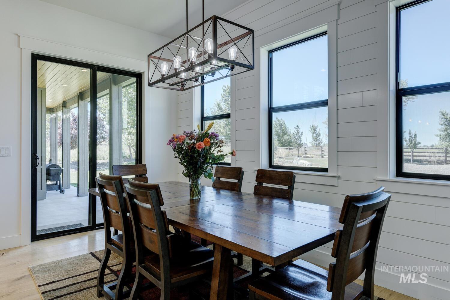 Dining space with a chandelier, light wood-type flooring, and wood walls