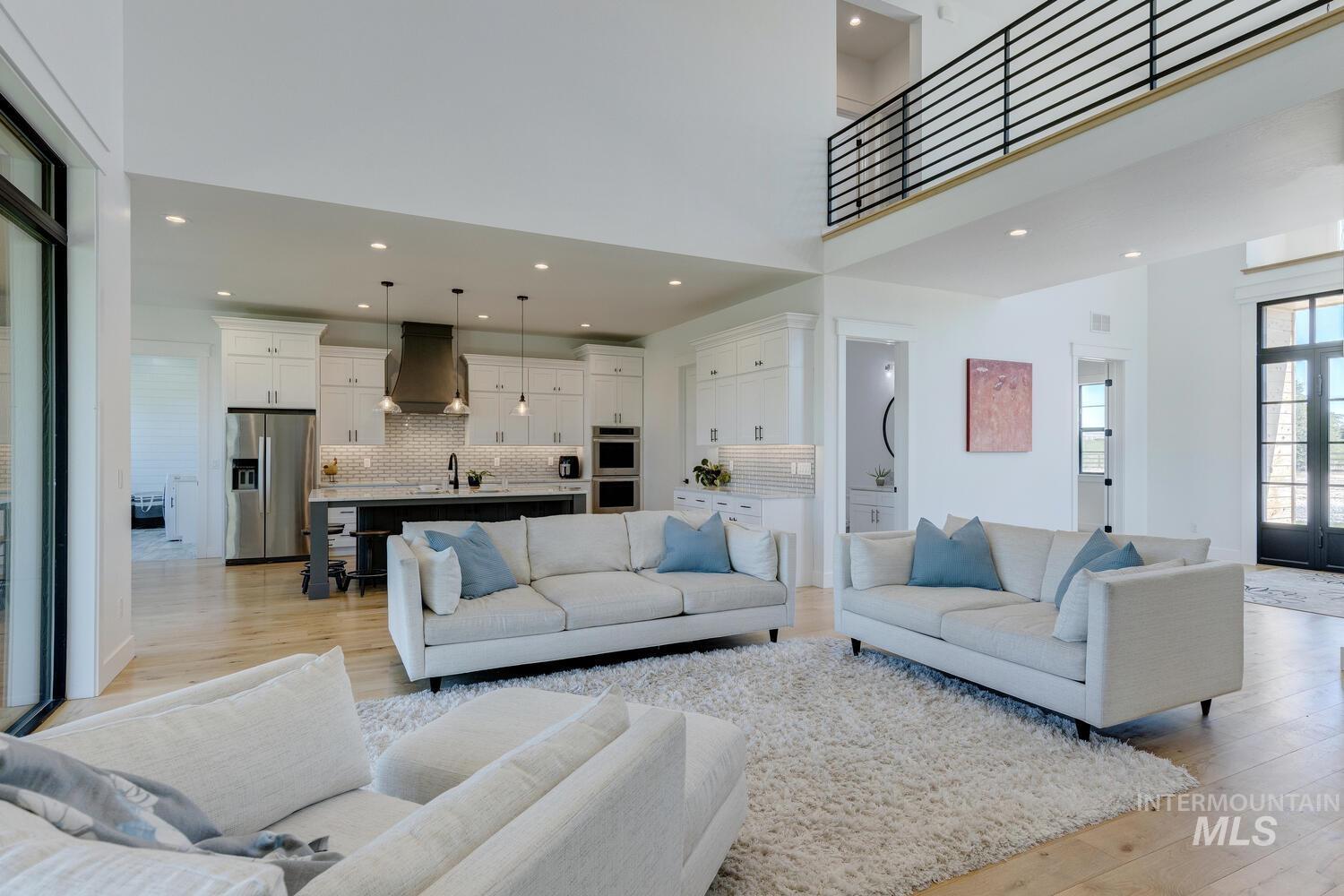 Living area featuring light wood-style flooring, recessed lighting, and a towering ceiling