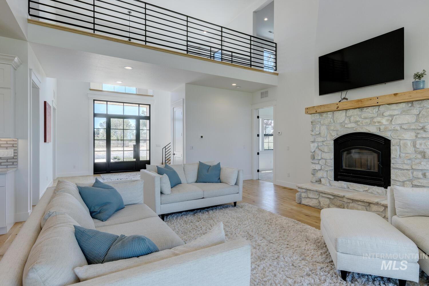 Living area with light wood-style floors, a fireplace, and a high ceiling