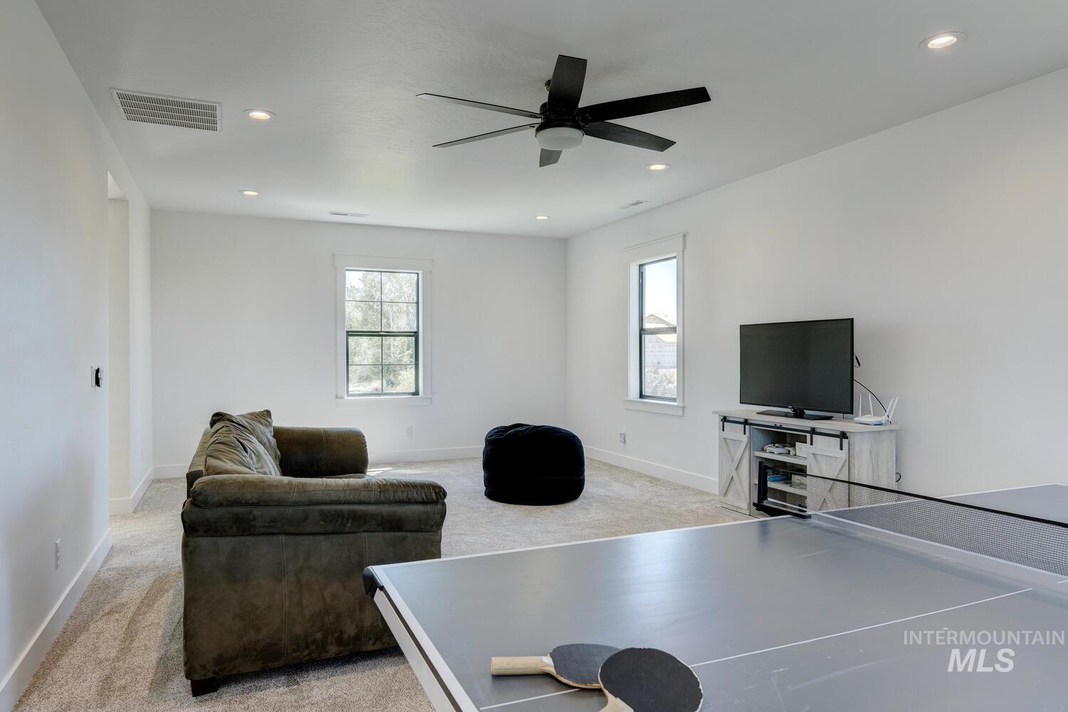 Living room with light colored carpet, a ceiling fan, and recessed lighting