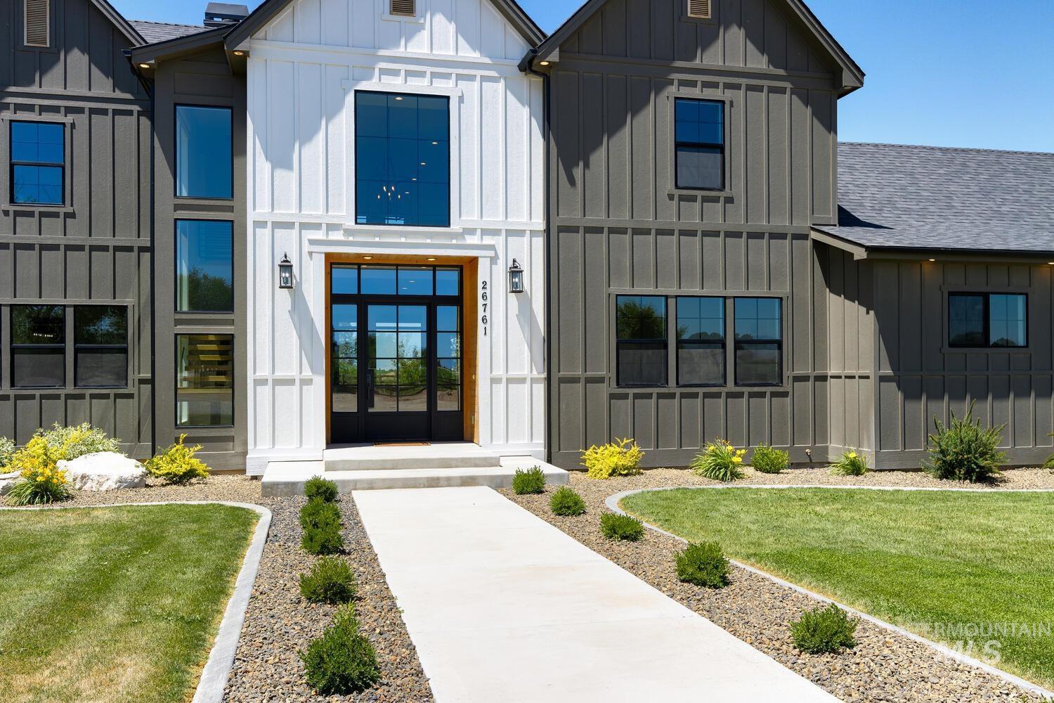 View of front facade with board and batten siding, roof with shingles, and a front yard
