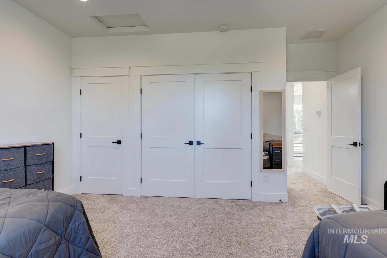 Bedroom featuring light carpet, a closet, and attic access