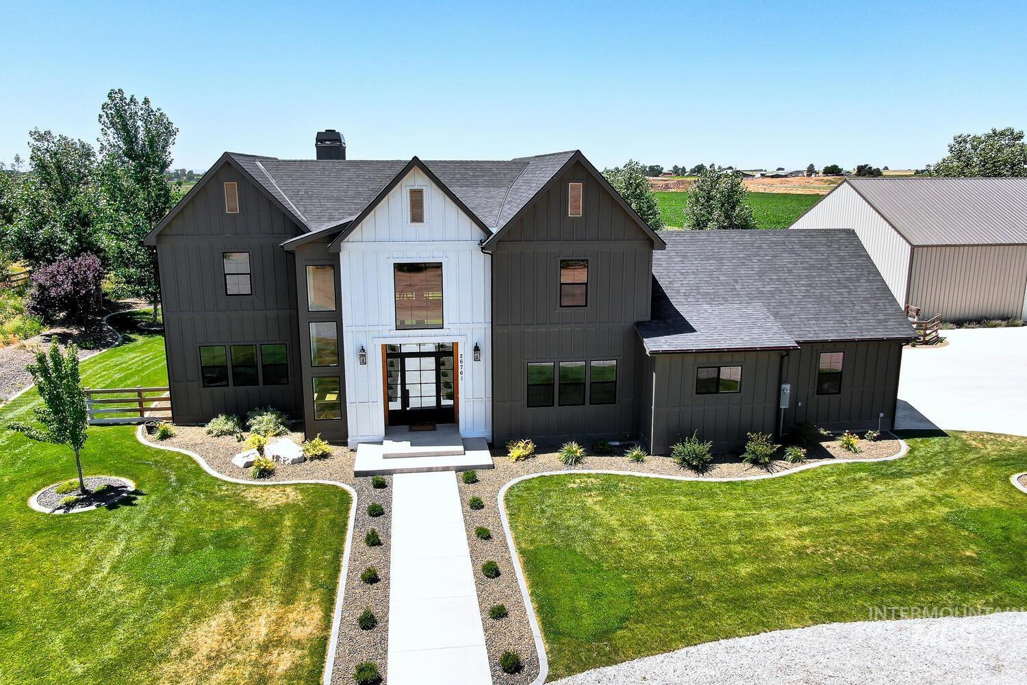 Modern farmhouse featuring board and batten siding, a shingled roof, and a chimney