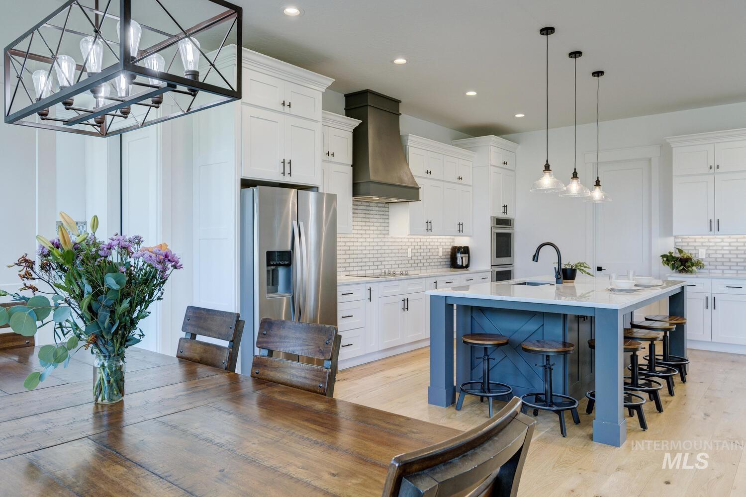 Kitchen featuring appliances with stainless steel finishes, custom range hood, decorative backsplash, light wood finished floors, and recessed lighting