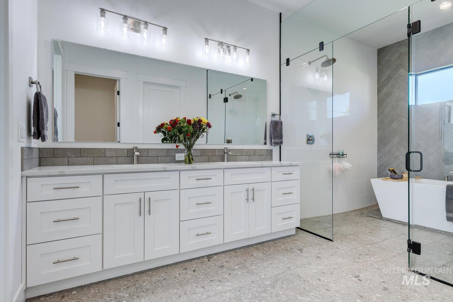 Full bathroom featuring double vanity, a shower stall, and a soaking tub