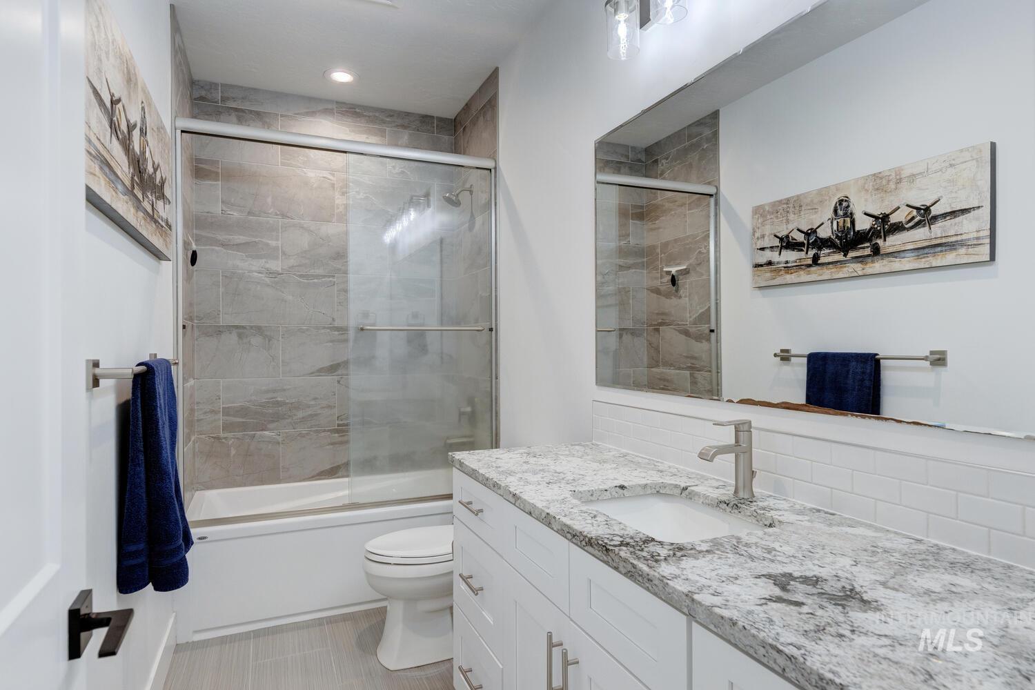 Bathroom with vanity, enclosed tub / shower combo, recessed lighting, and backsplash