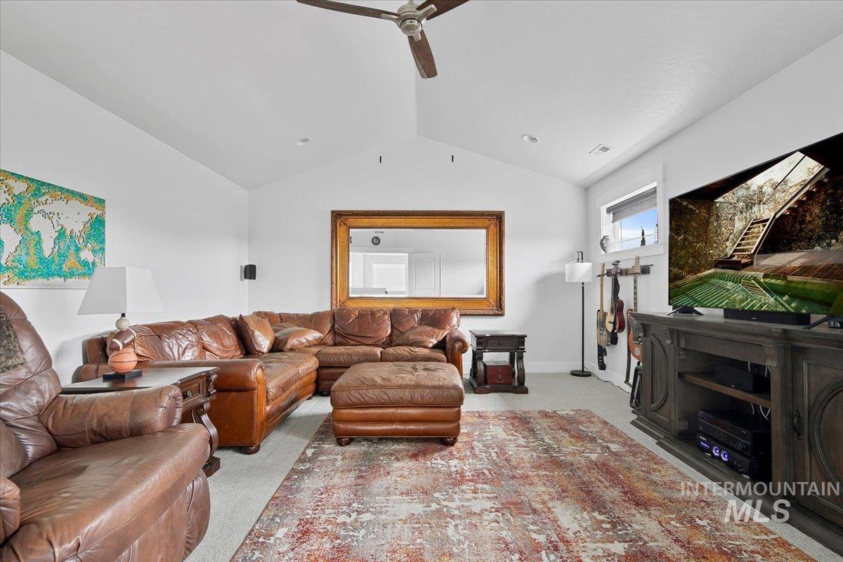 Living area featuring a vaulted ceiling with a ceiling fan, a large window with blinds, and recessed lighting