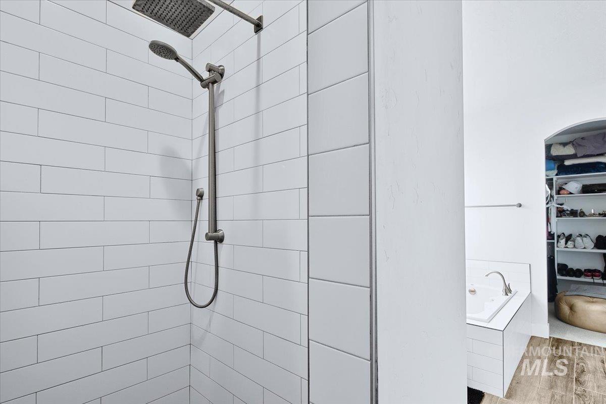 Shower featuring white subway tile surround, rain shower head, and hand-held shower fixture