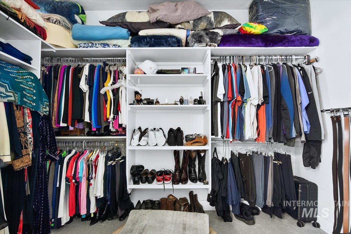 Built-in closet system featuring white shelving, multiple hanging rods, and integrated storage compartments