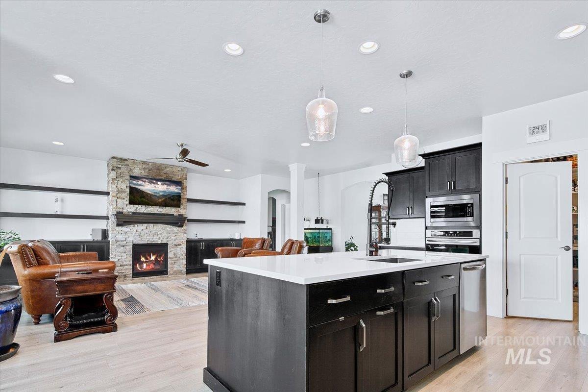 Kitchen island with a light-toned countertop, dark wood-finish cabinetry, and an integrated stainless steel dishwasher