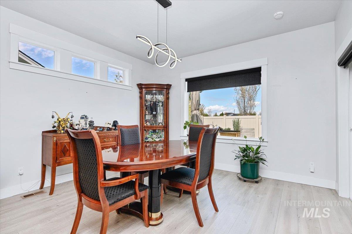 Dining area featuring light wood-finish flooring, a large window with a black roller shade, and a row of high transom windows