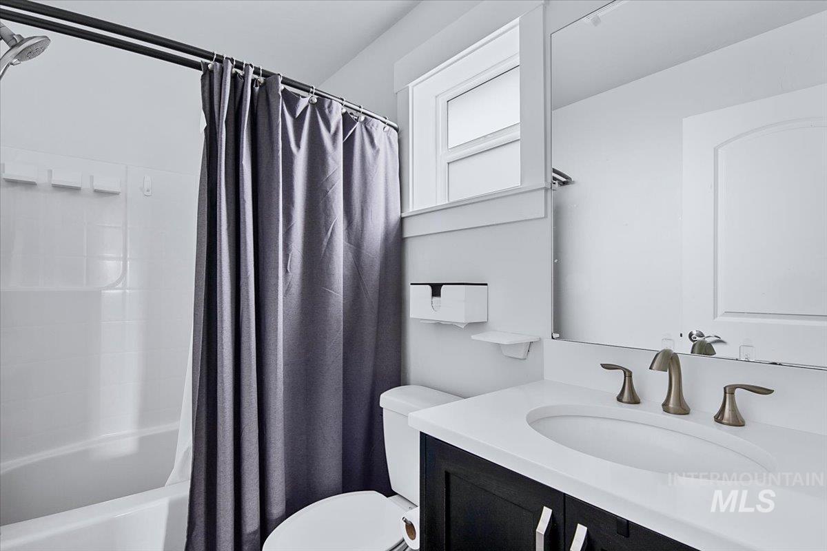 Bathroom featuring a built-in tub with a white subway tile surround, dark wood-finish vanity with a white countertop, an integrated sink, and bronze-finish fixtures