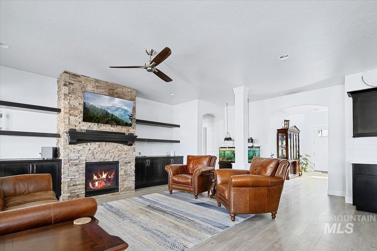 Living space featuring a stone-clad fireplace surround with a dark wood mantel, built-in open shelving, and lower cabinetry