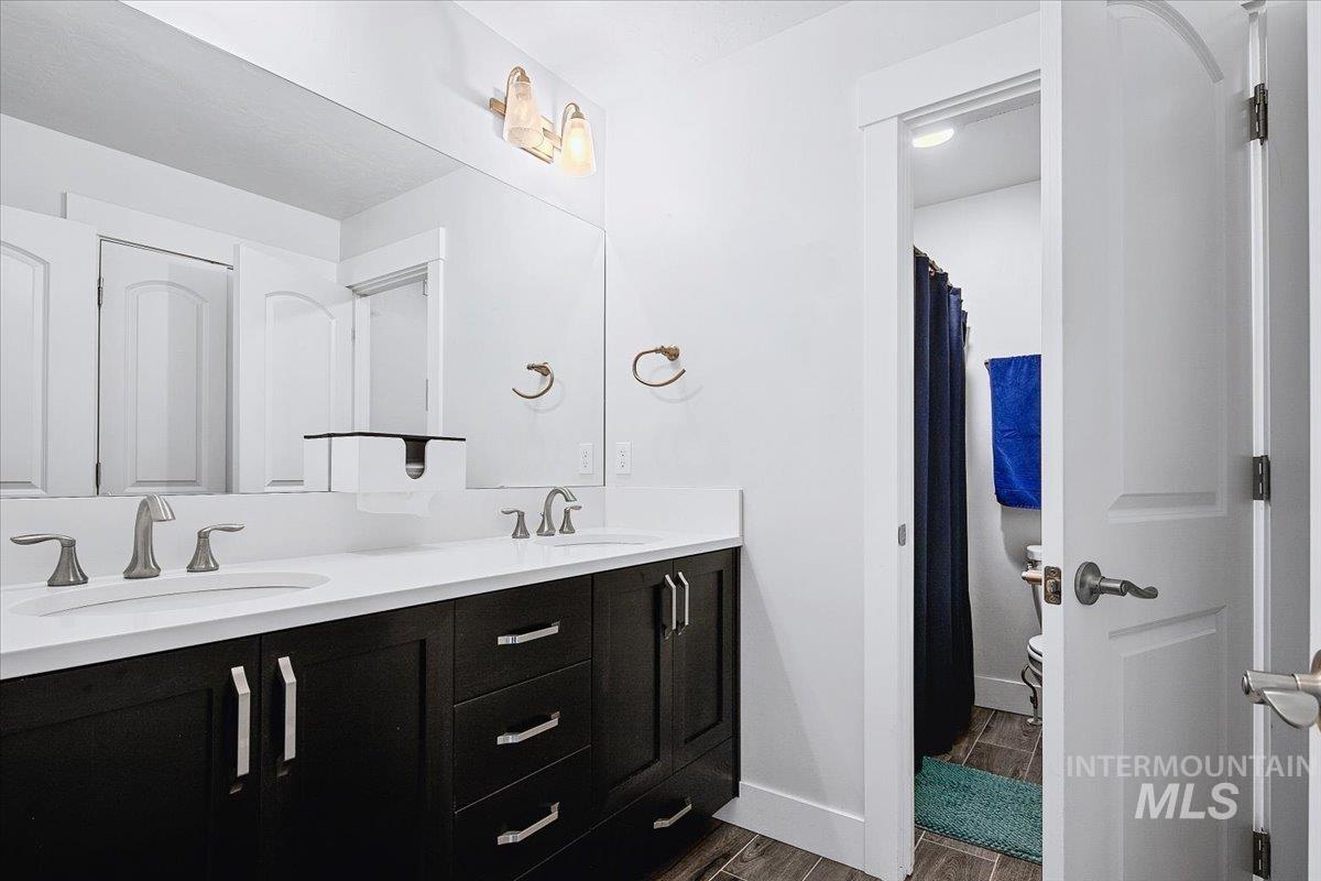 Dual vanity featuring dark wood cabinetry, white countertops, and brushed nickel fixtures