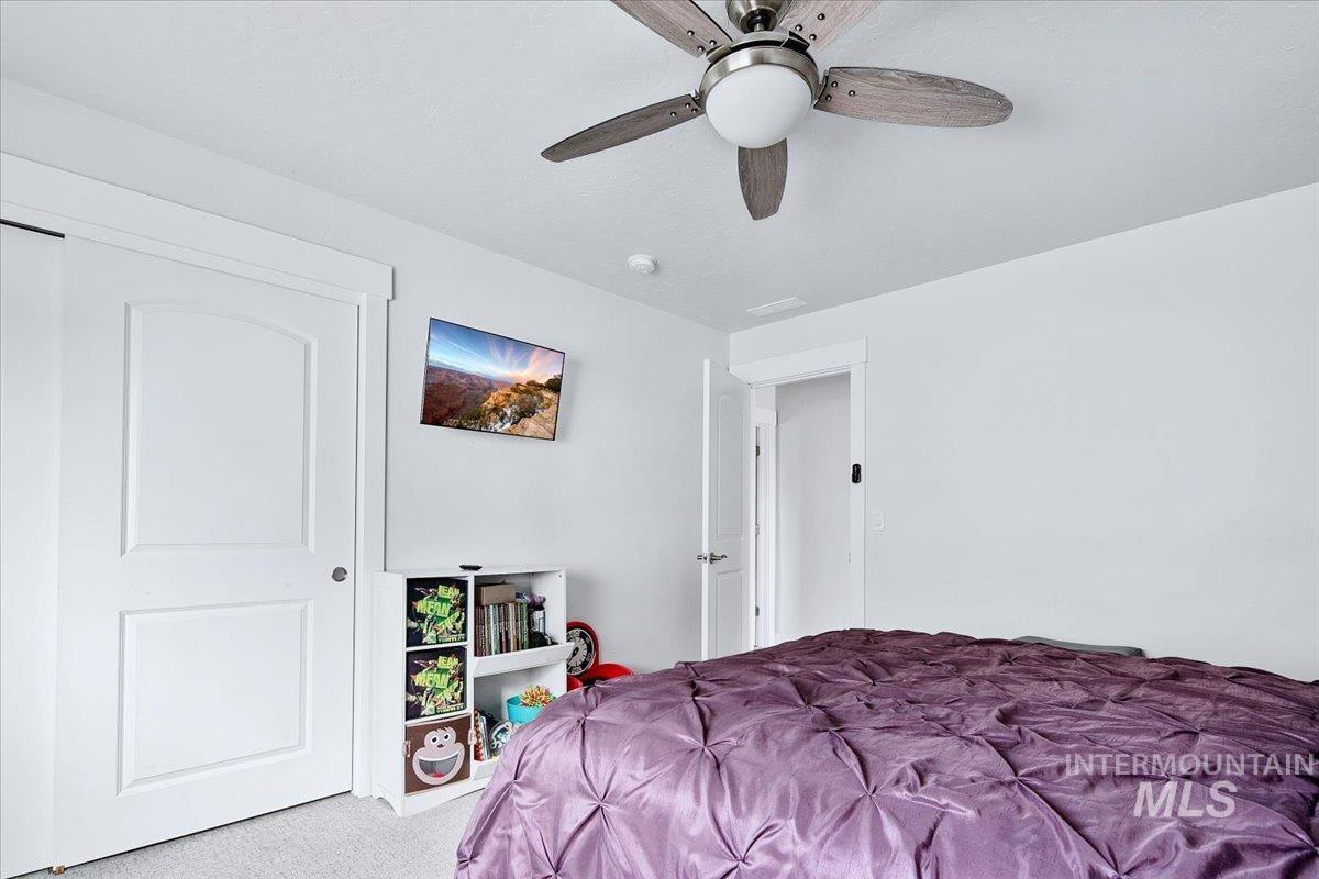Interior room featuring a ceiling fan with wood-finish blades, white painted walls, and white trim