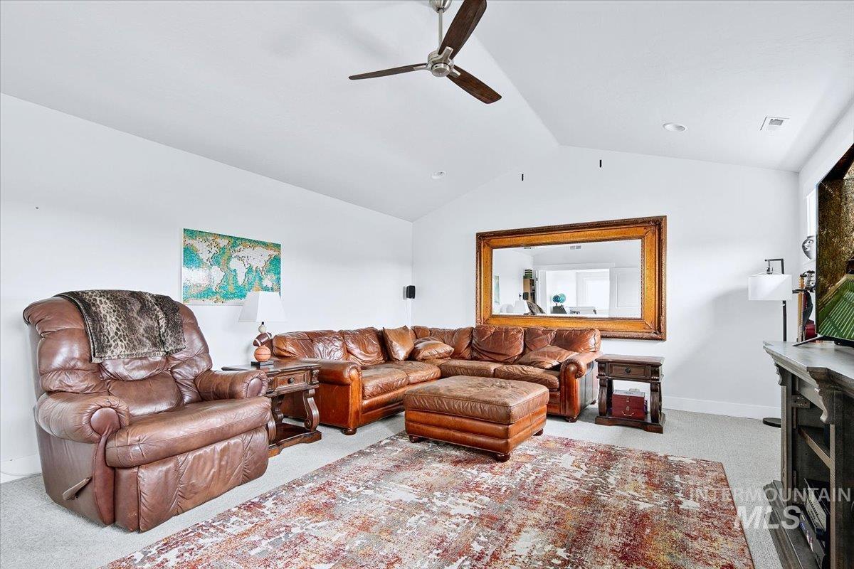 Spacious living area featuring a vaulted ceiling with an exposed beam, recessed lighting, and a ceiling fan