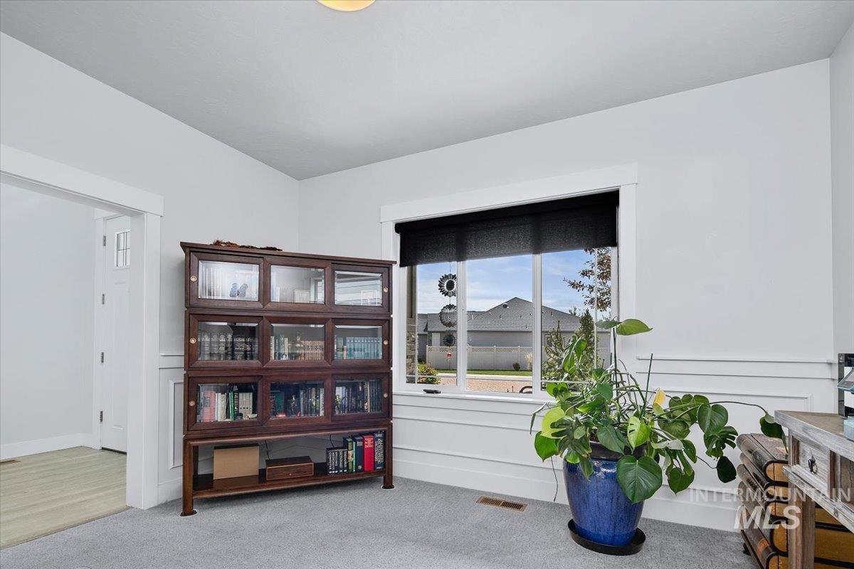 White walls featuring wainscoting and a large window with black roller shades