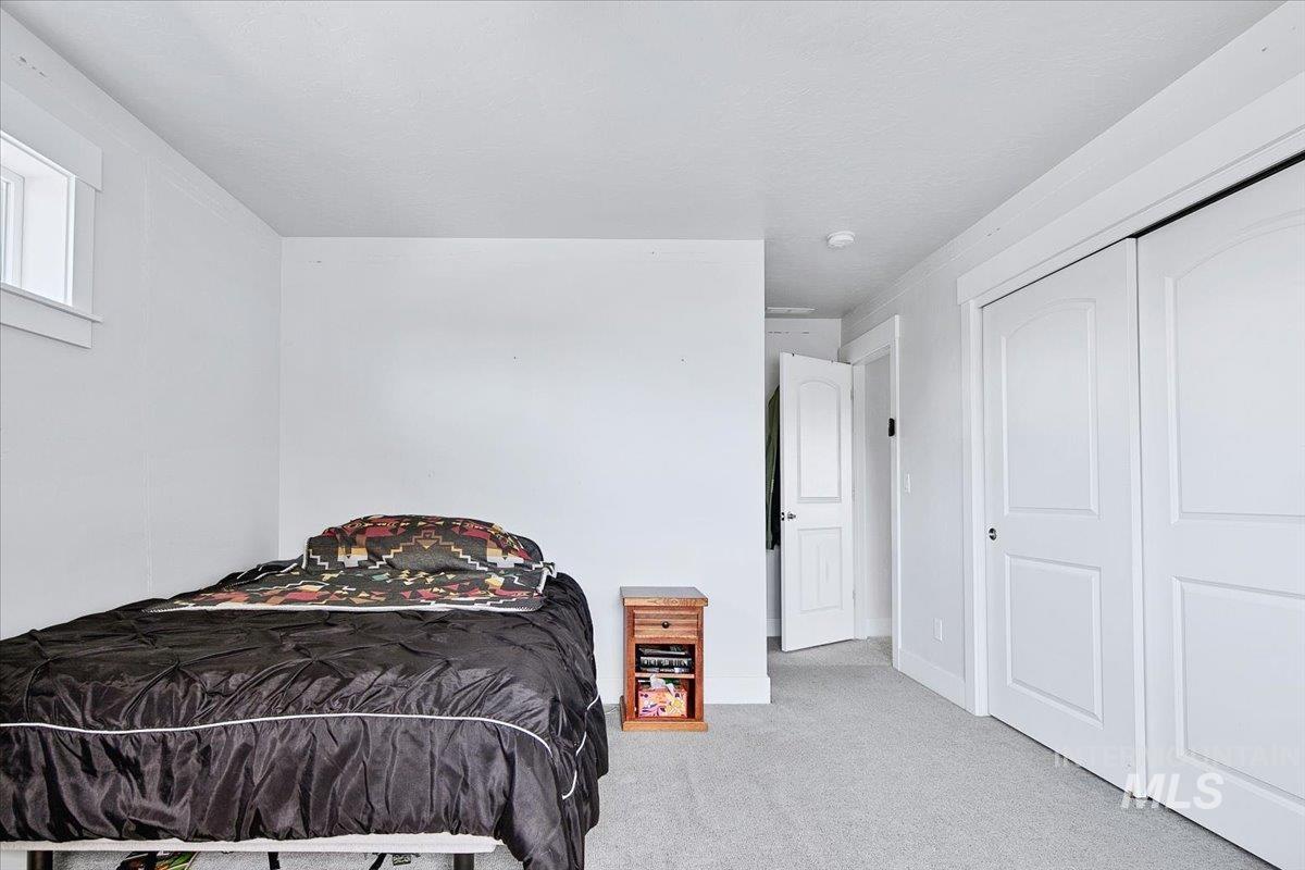 Neutral-toned carpeting complements the white walls and trim throughout this space, featuring two-panel interior doors, a window with white casing, and a recessed light fixture