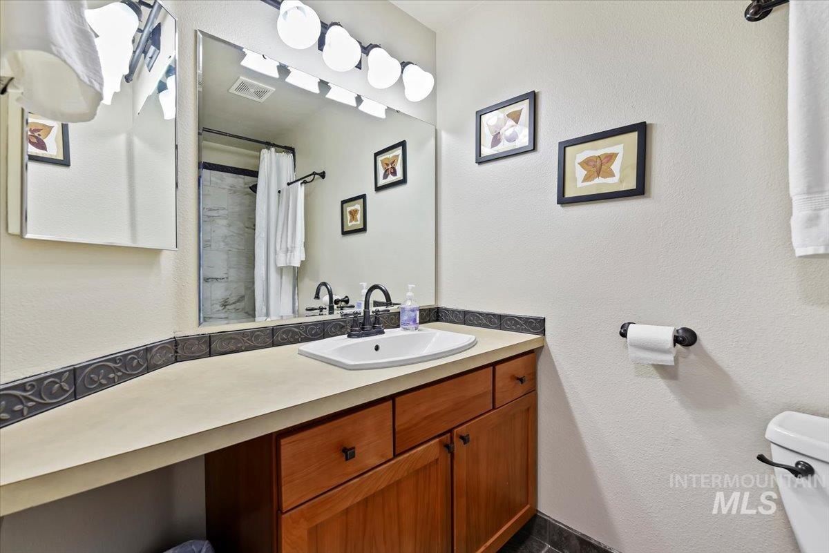 Full bath with a textured wall, vanity, and a shower with shower curtain