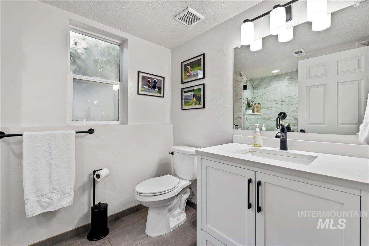Bathroom with vanity, a textured ceiling, a marble finish shower, and light tile patterned floors