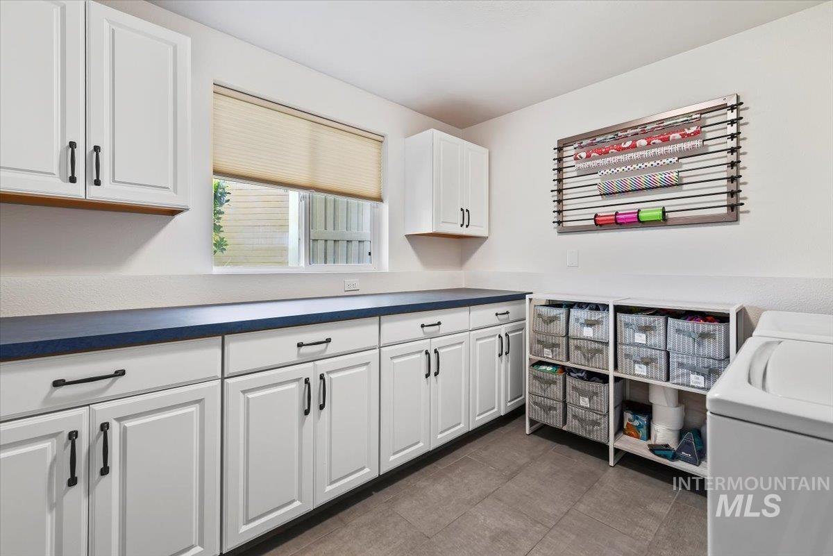 Laundry Room  featuring dark countertops, white cabinets, dark tile patterned flooring, and washer and dryer