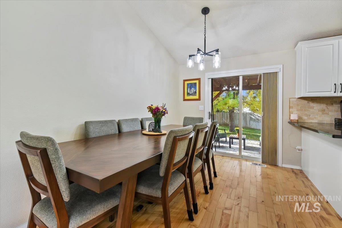 Dining room with light wood-style floors, lofted ceiling, and a chandelier
