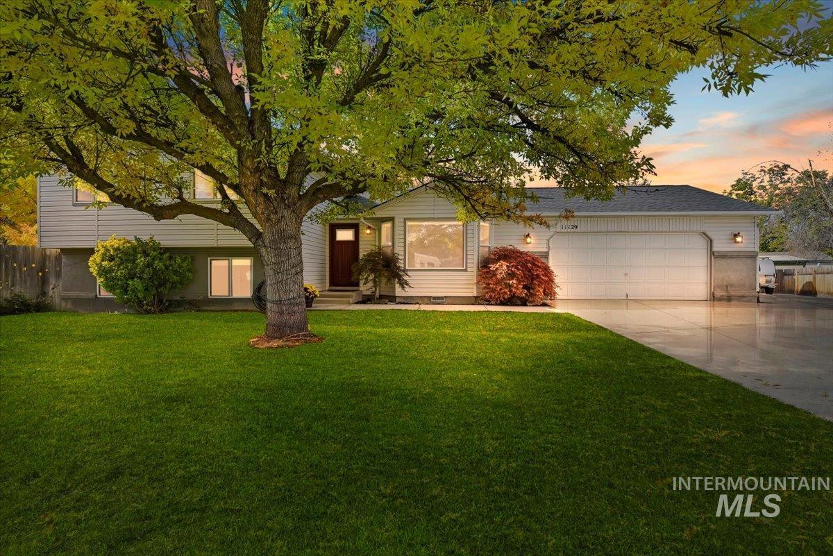 View of front of property with driveway, a front yard, and an attached garage
