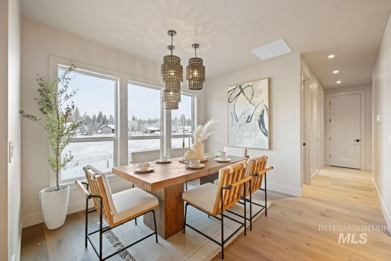 Dining space with light wood finished floors, a chandelier, and recessed lighting