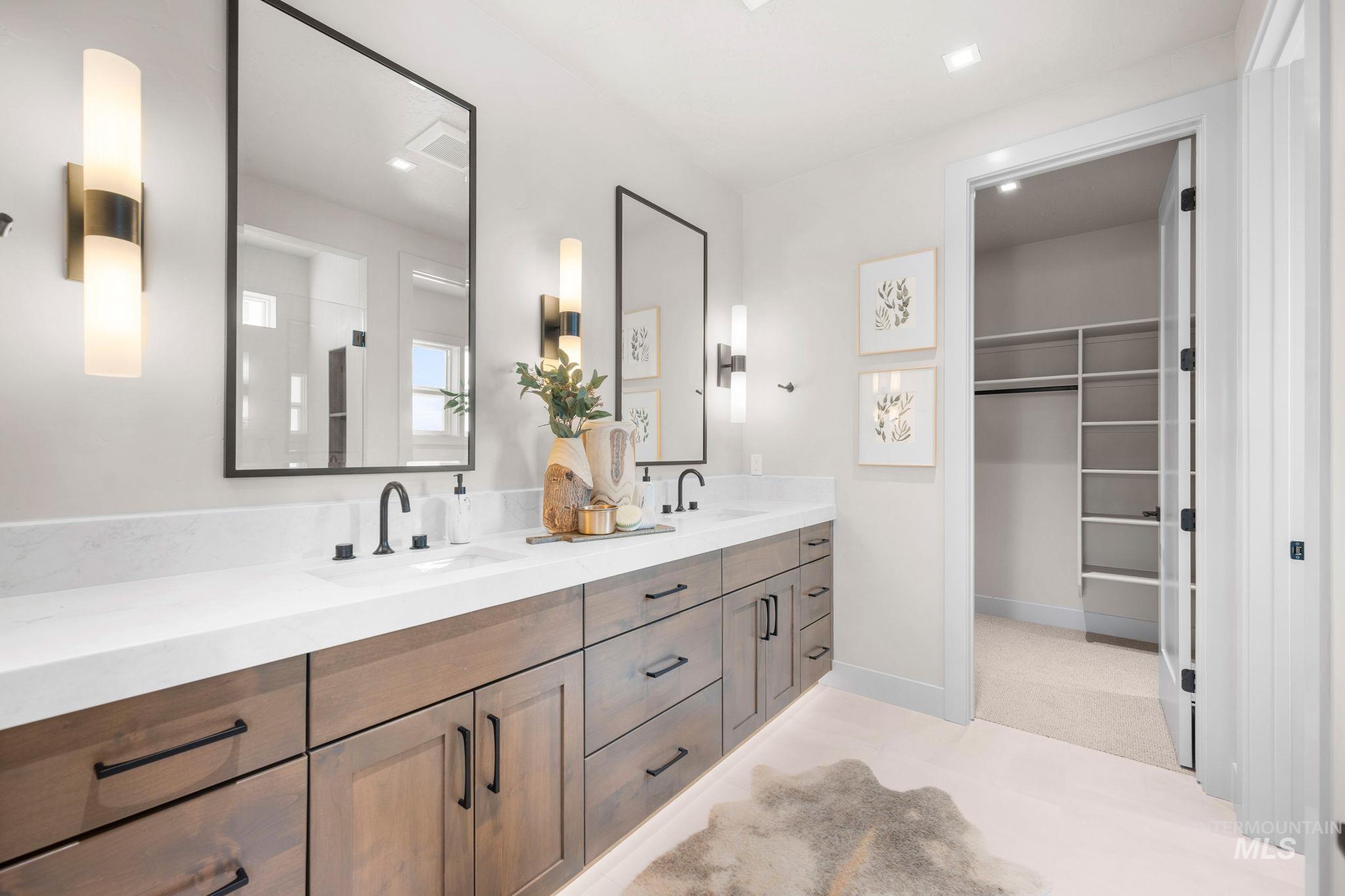 Primary Bathroom featuring double vanity, a walk in closet, an enclosed shower, and light carpet