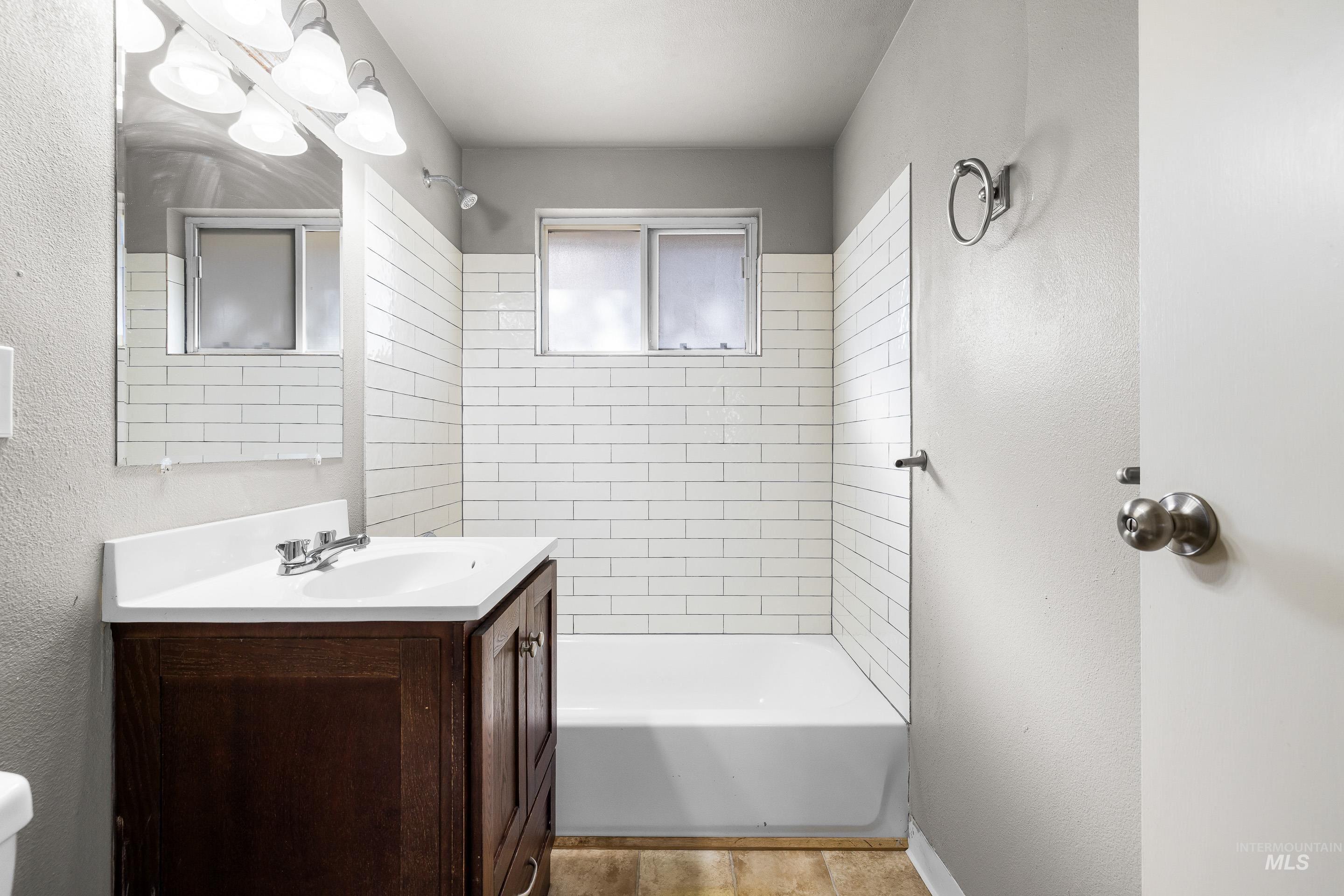 Full bathroom featuring a textured wall, shower / bathtub combination, and vanity