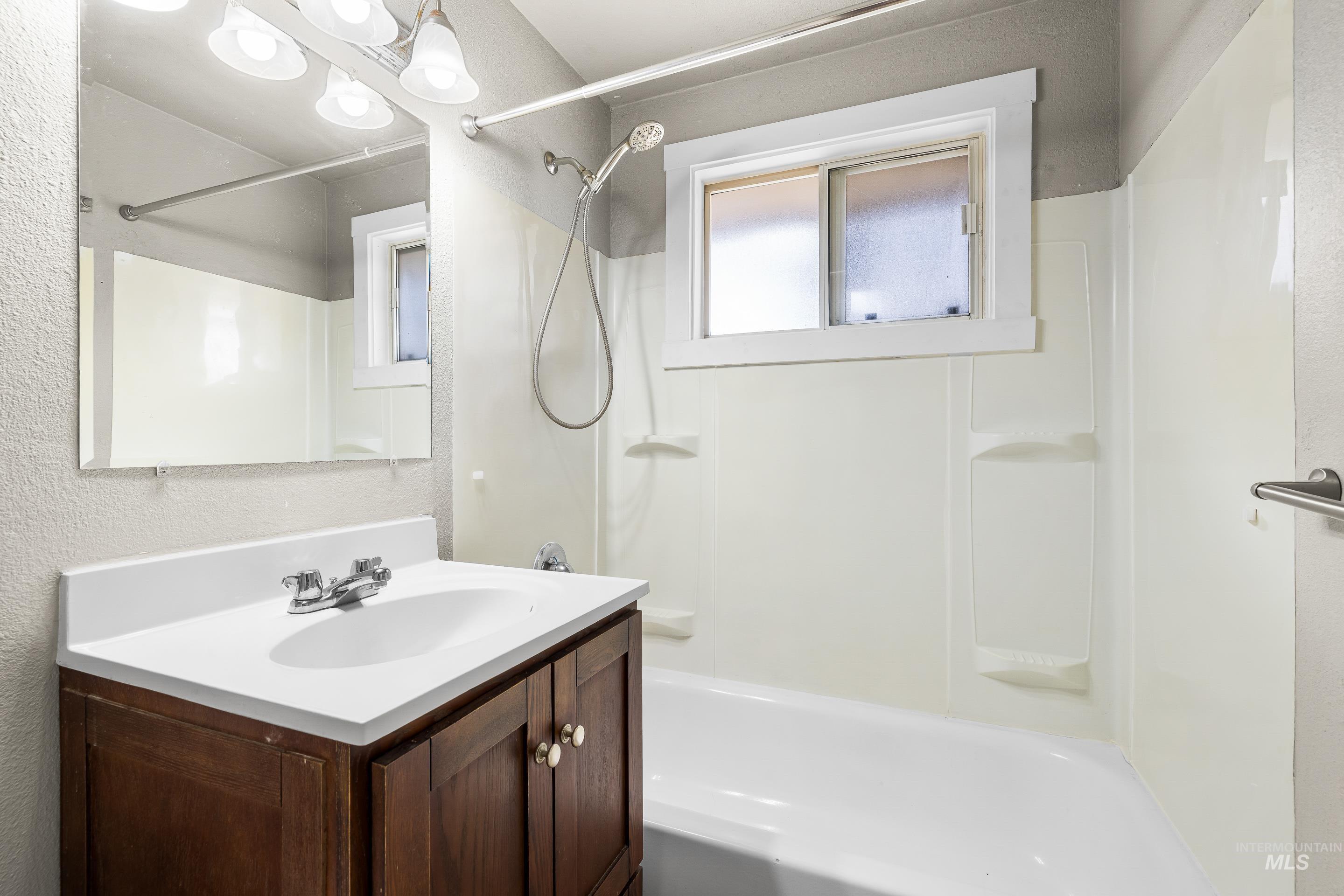 Full bathroom with vanity,  shower combination, and a textured wall