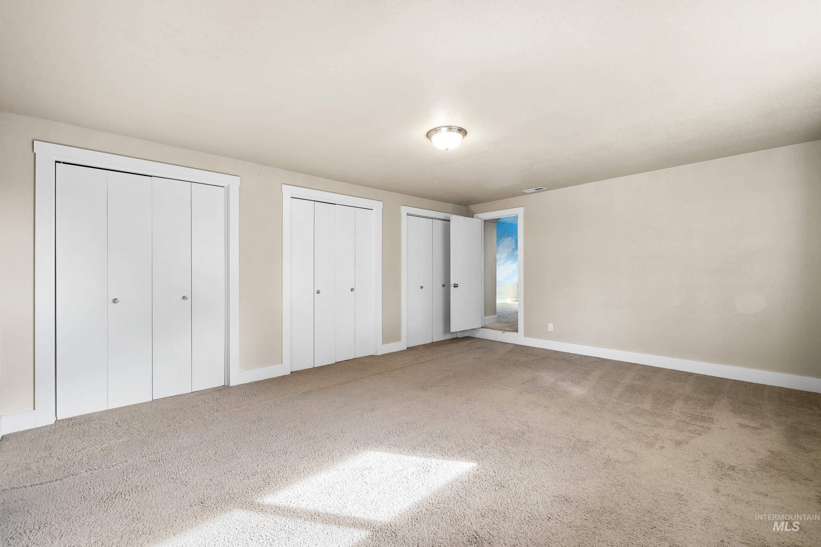 Bedroom / bonus room with multiple closets and light colored carpet