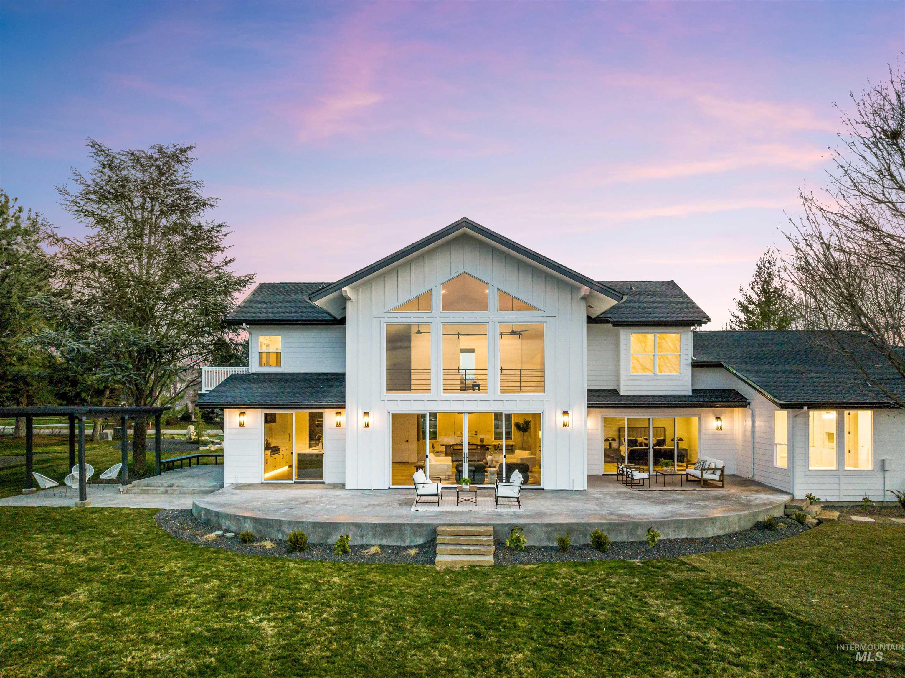 Back of property with board and batten siding, a patio, a yard, and a shingled roof