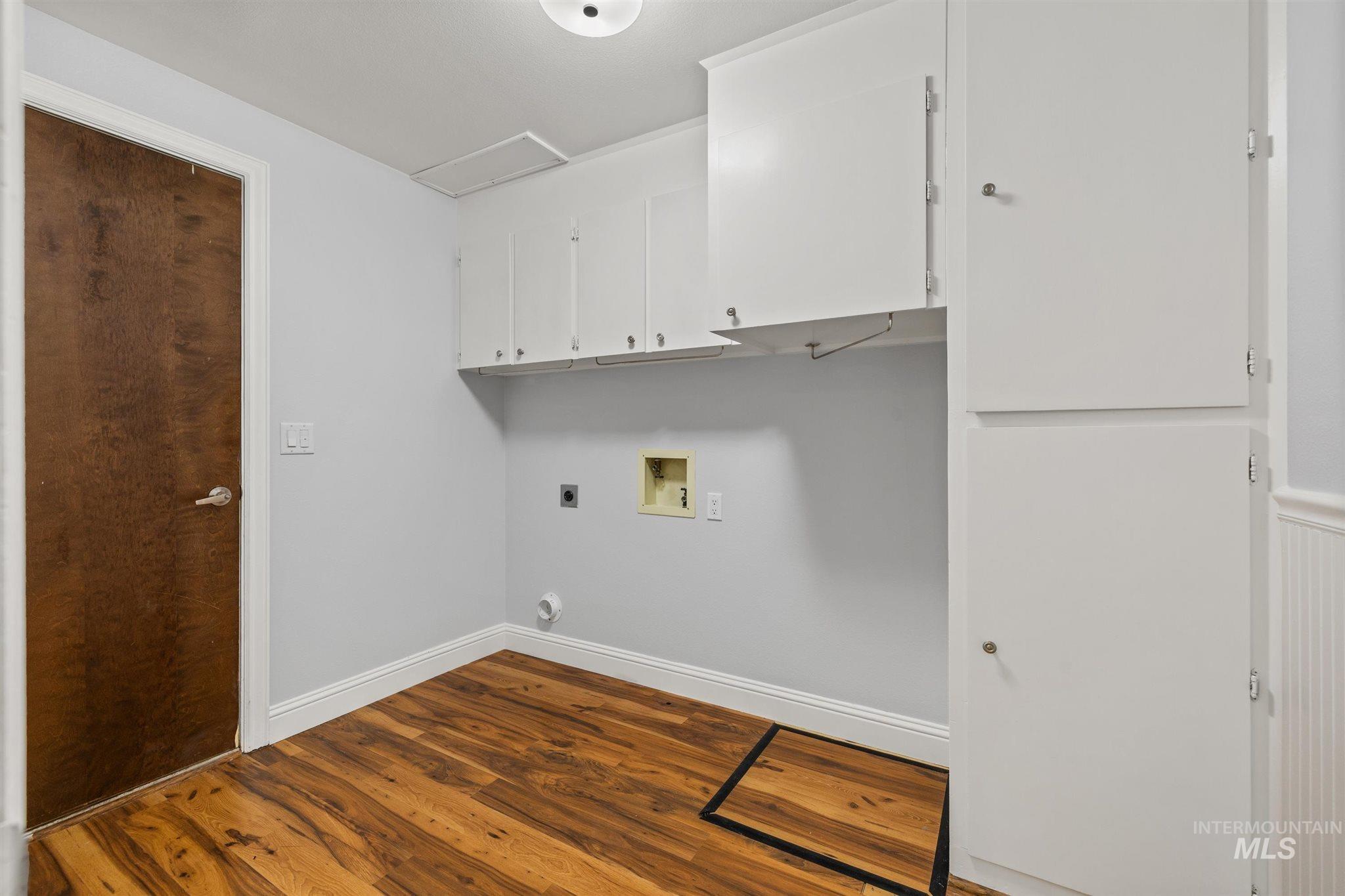 Laundry area with dark wood-style flooring, cabinet space, hookup for a washing machine, and electric dryer hookup