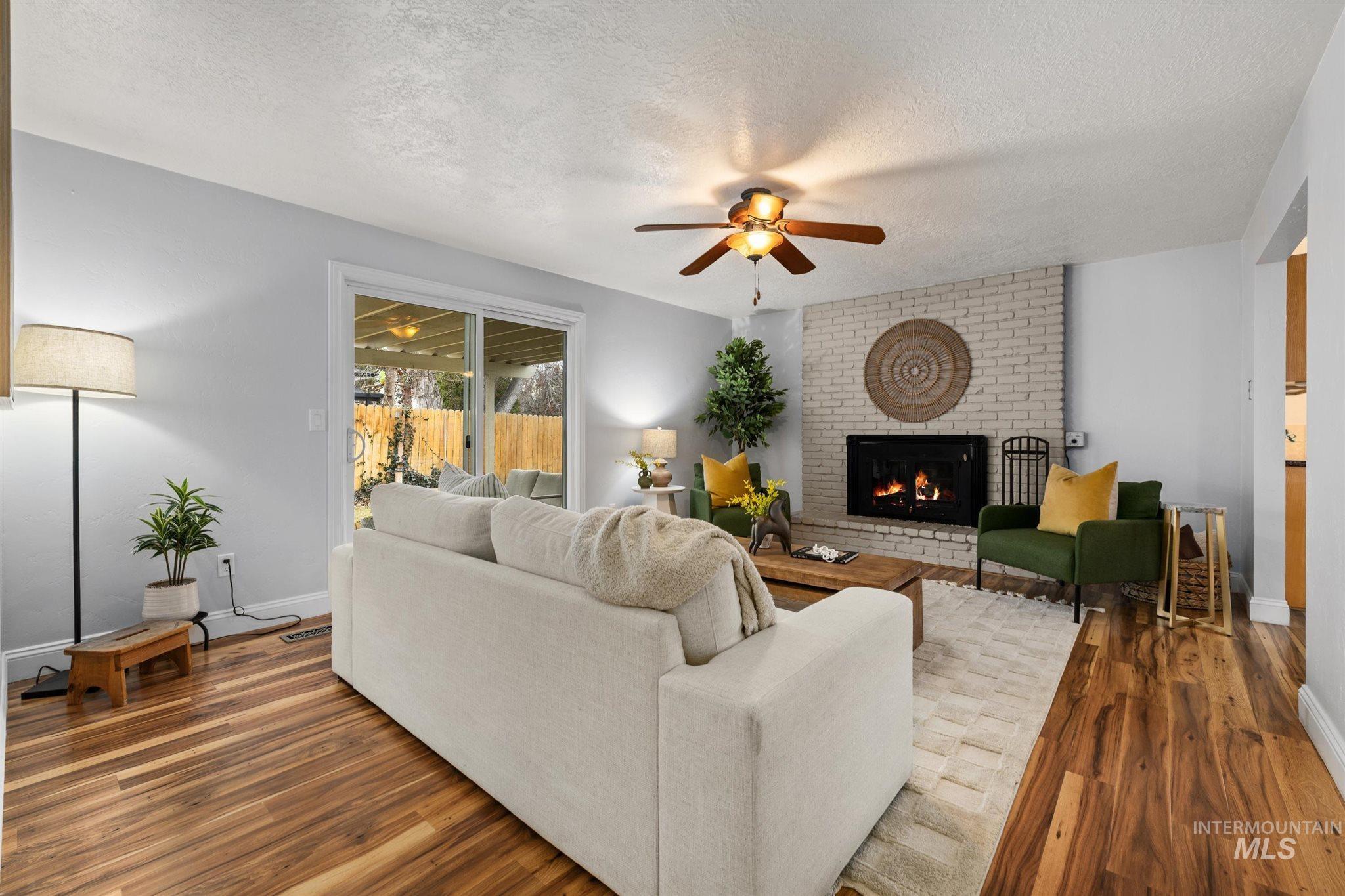 Living area with a textured ceiling, a fireplace, wood finished floors, and ceiling fan